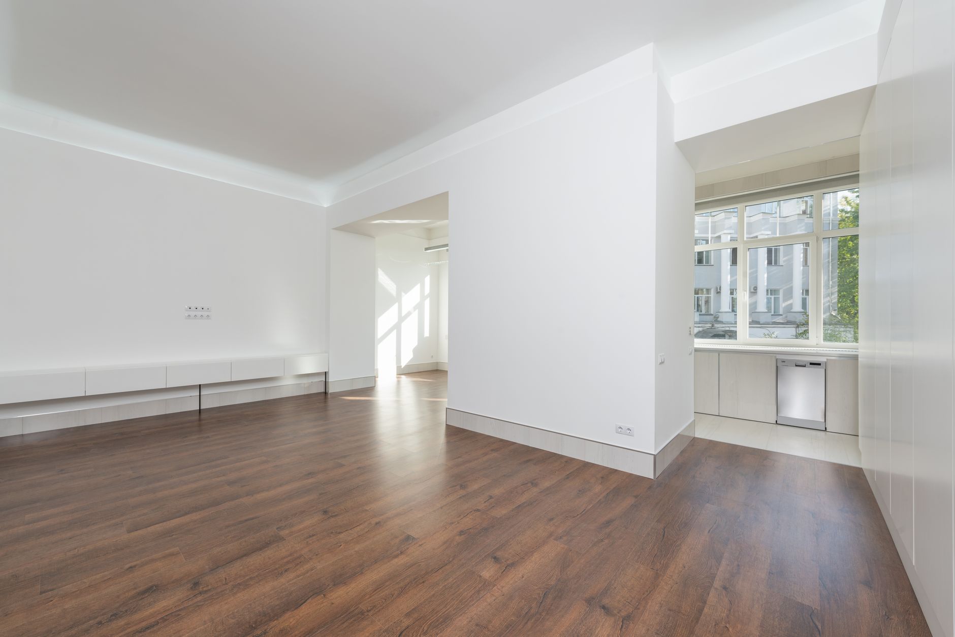 A minimalist living room with one sofa, a single side table, and an empty shelf against a plain wall.