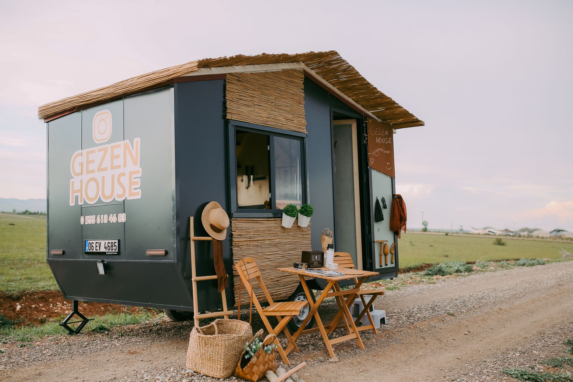 Small single-story tiny house with a compact porch sitting on a gravel lot